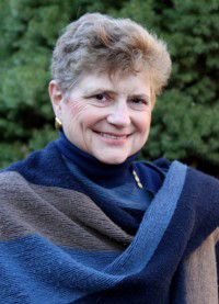 A woman with short hair wearing a blue and brown scarf.